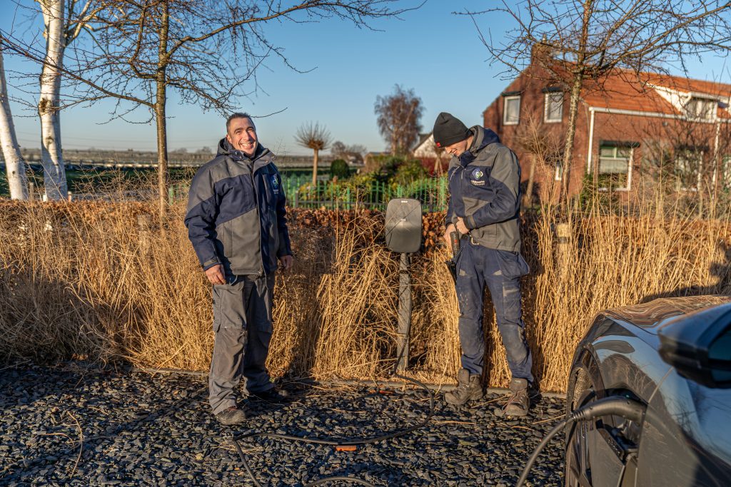 Foto van blije medewerkers van Coppens Energie die een laadpaal installeren